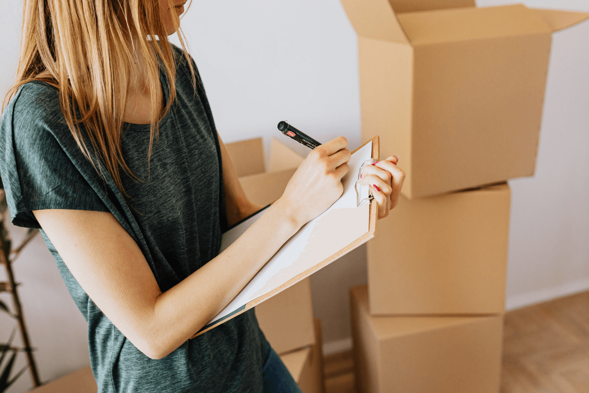 Mulher segurando prancheta conferindo caixas de papelão, representando a logística complexa que o afiliado evita ao lucrar sem ter estoque no marketing digital.